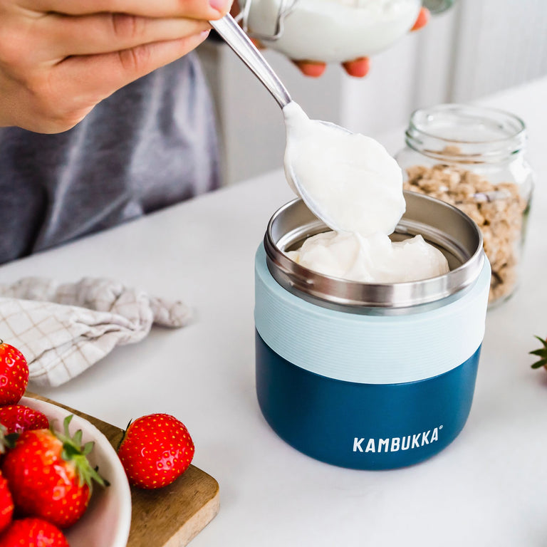 Een persoon schept yoghurt in een Kambukka Bora Luncbox 400 ml