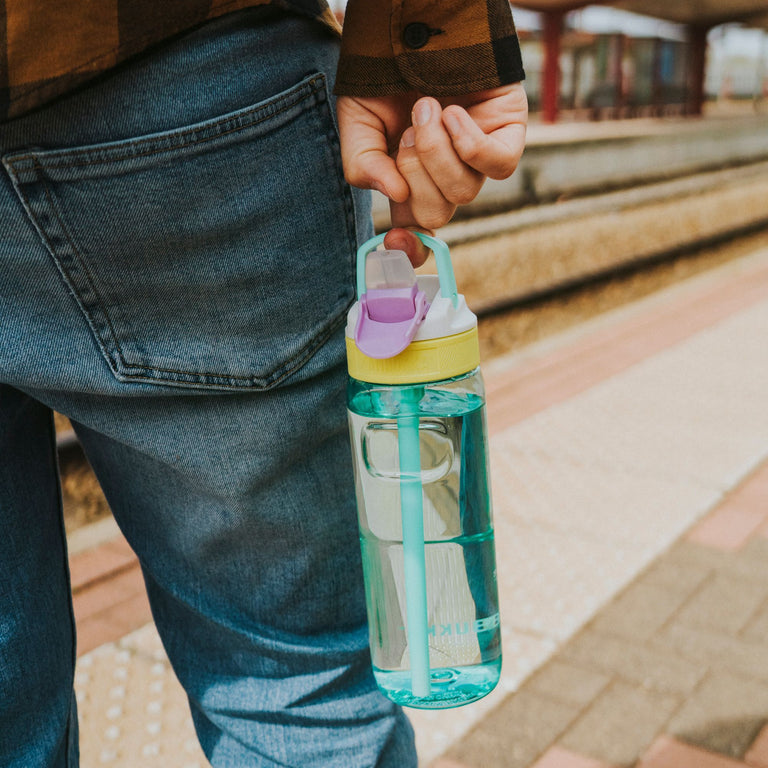 Kambukka Lagoon 750 ml Candy Dance Waterfles vastgehouden door een man aan het treinperron